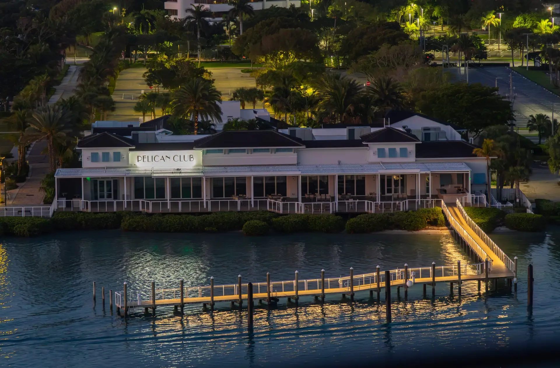 The Pelican Club lit at dusk, its long dock reaching out over the water